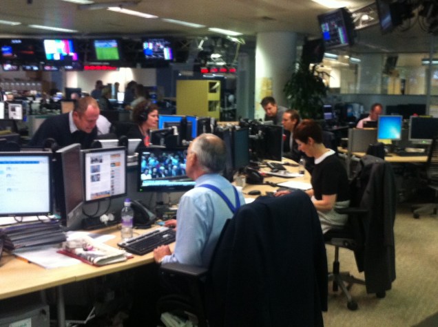 ITV News's Alastair Stewart consults with colleagues at a desk in the ITN London studio